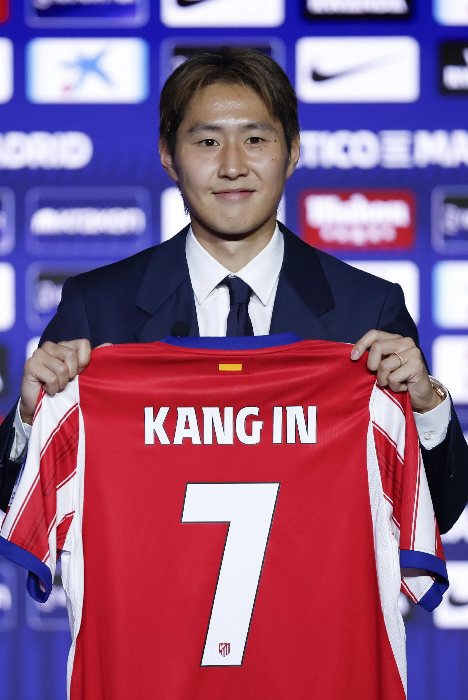 정장을 입고 KANG IN 7 마킹이 된 아틀레티코 마드리드 홈 유니폼을 들어 보이는 이강인
