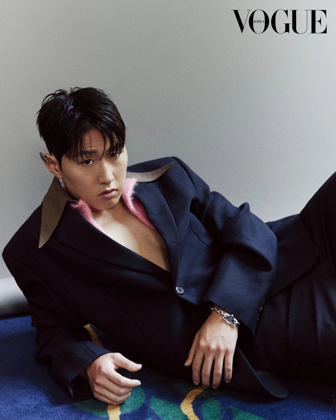 프라다 네이비 재킷과 검정 팬츠를 입고 파란 카펫에 기대 누운 이강인의 보그 코리아 화보