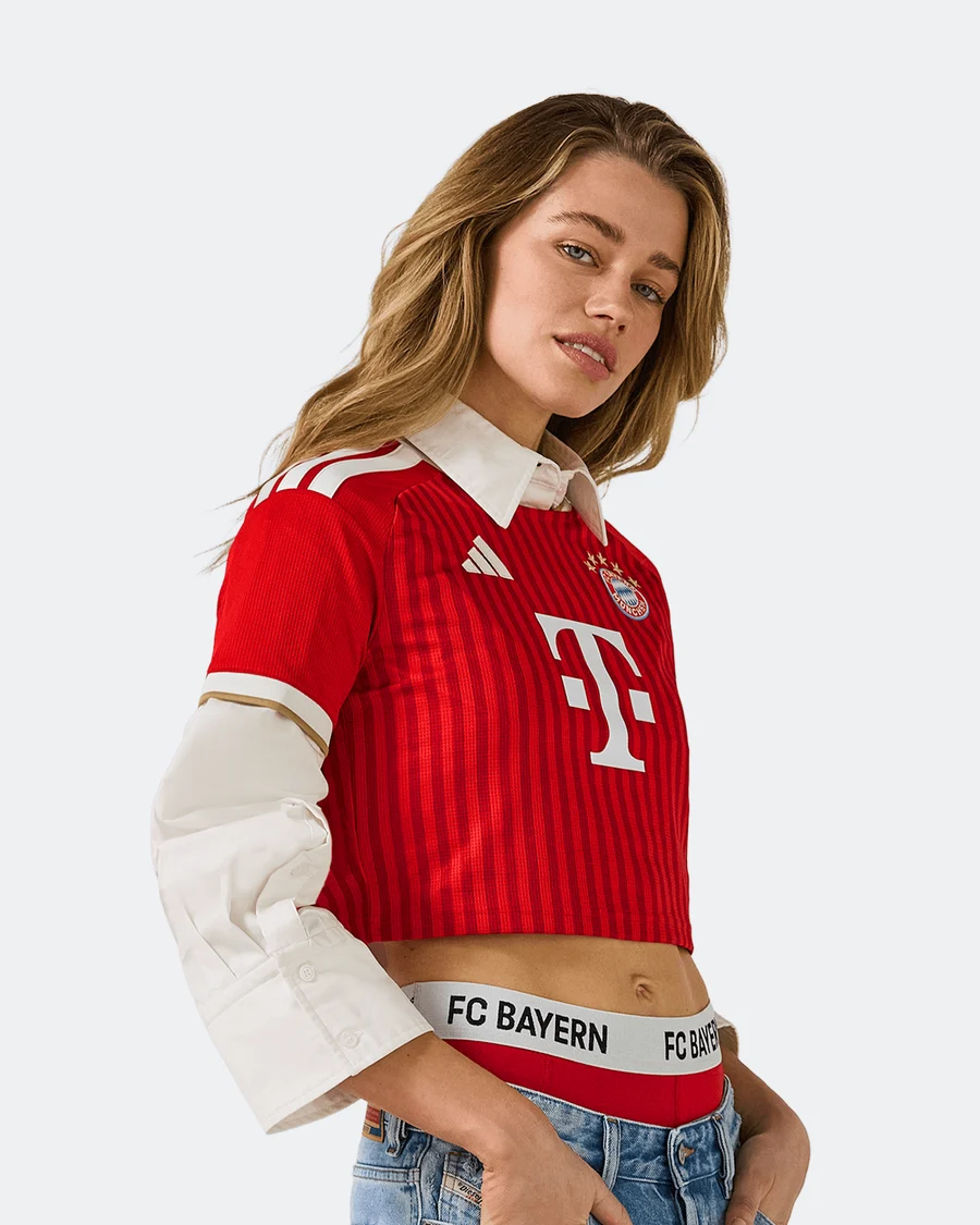 FC 바이에른 뮌헨 2026/27 여성 크롭 홈 저지 안에 흰 셔츠를 겹쳐 입고 허리에 FC BAYERN 밴드를 드러낸 모델