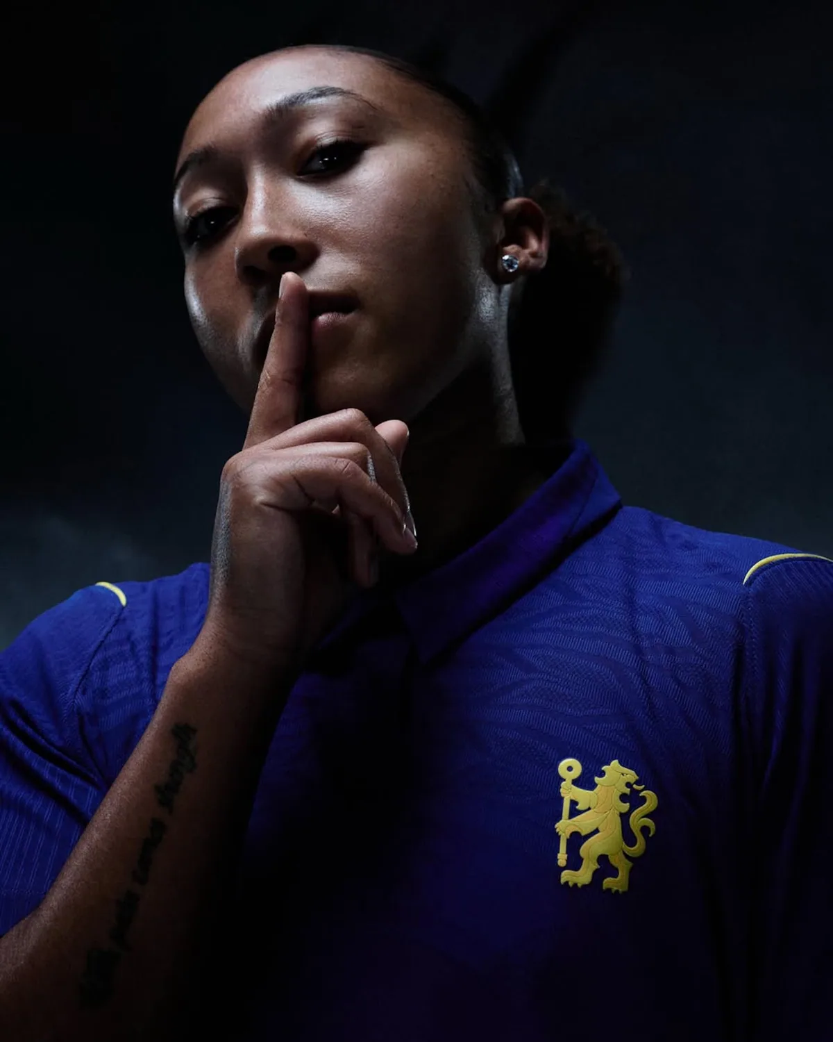 검지를 입술에 대고 조용히 하라는 몸짓을 하며 첼시 2026/27 홈 유니폼을 입은 로런 제임스