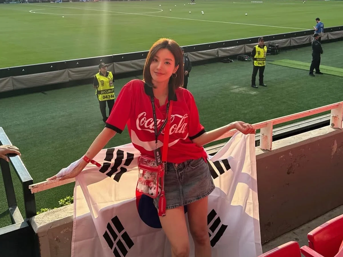 빨간 코카콜라 유니폼과 데님 미니스커트 차림으로 태극기를 펼친 권은비와 과달라하라 경기장