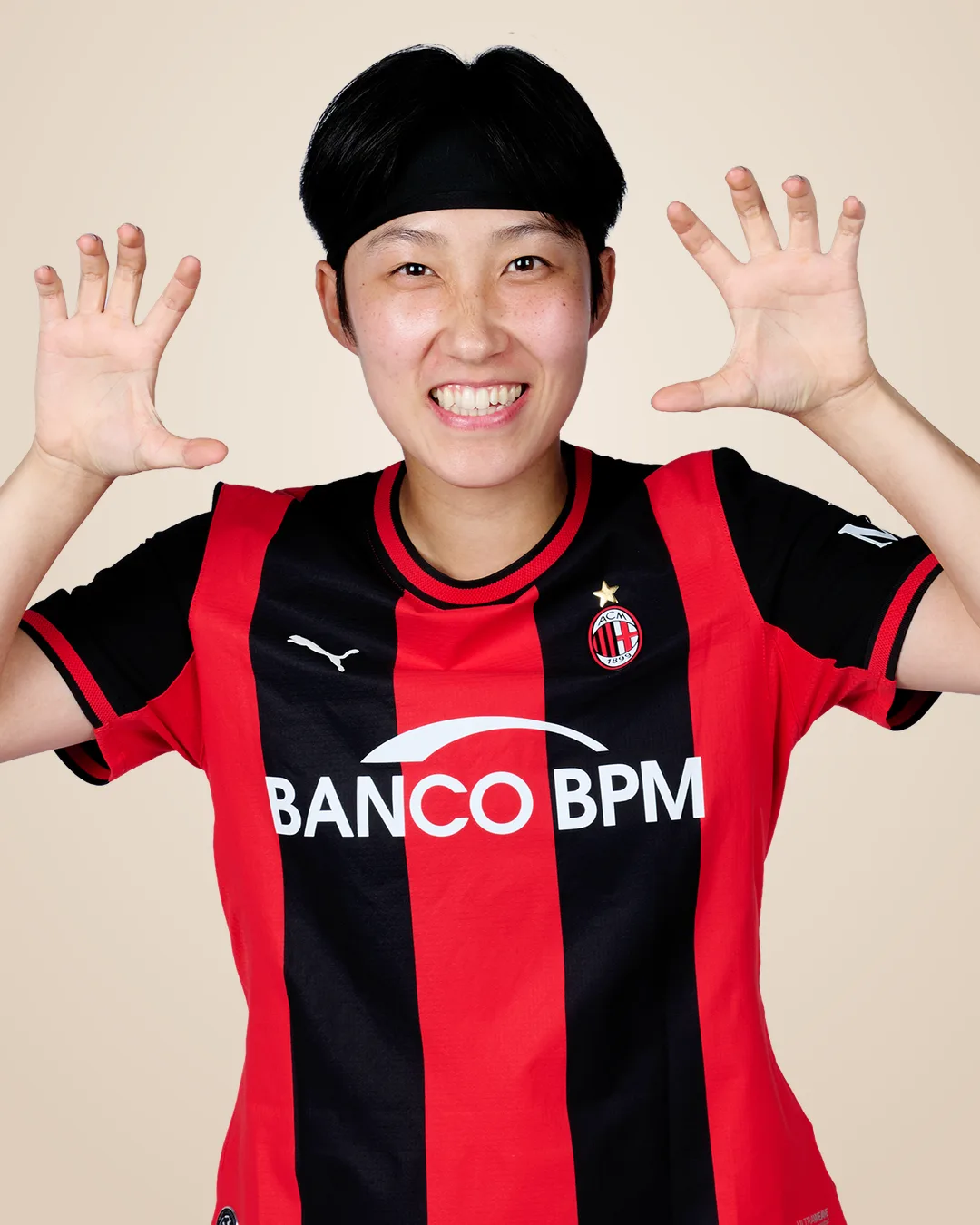두 손을 얼굴 옆으로 들어 올리고 활짝 웃는 AC 밀란 2026/27 홈 유니폼 차림의 박수정