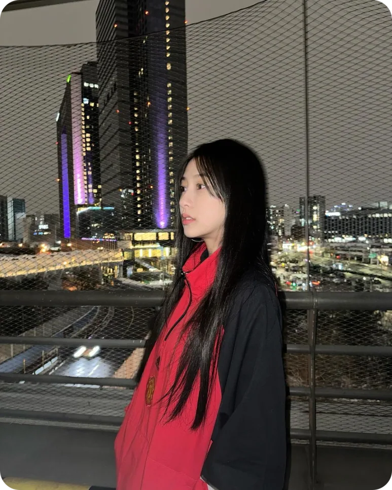 도시 야경과 맨유 셸 파카의 빨강이 대비되는 인물 사진