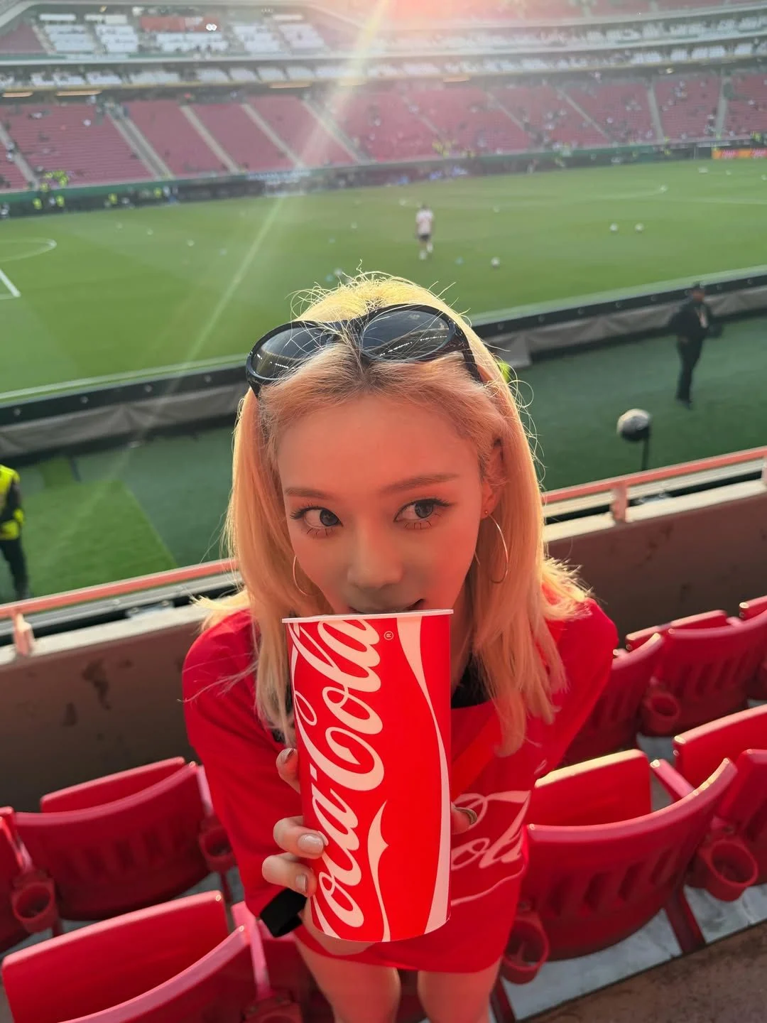 빨간 코카콜라 축구 저지를 입고 붉은 컵을 든 윈터와 과달라하라 경기장