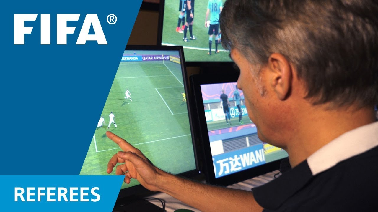 여러 경기 화면을 가리키며 VAR 판독 장면을 확인하는 FIFA 심판 전문가