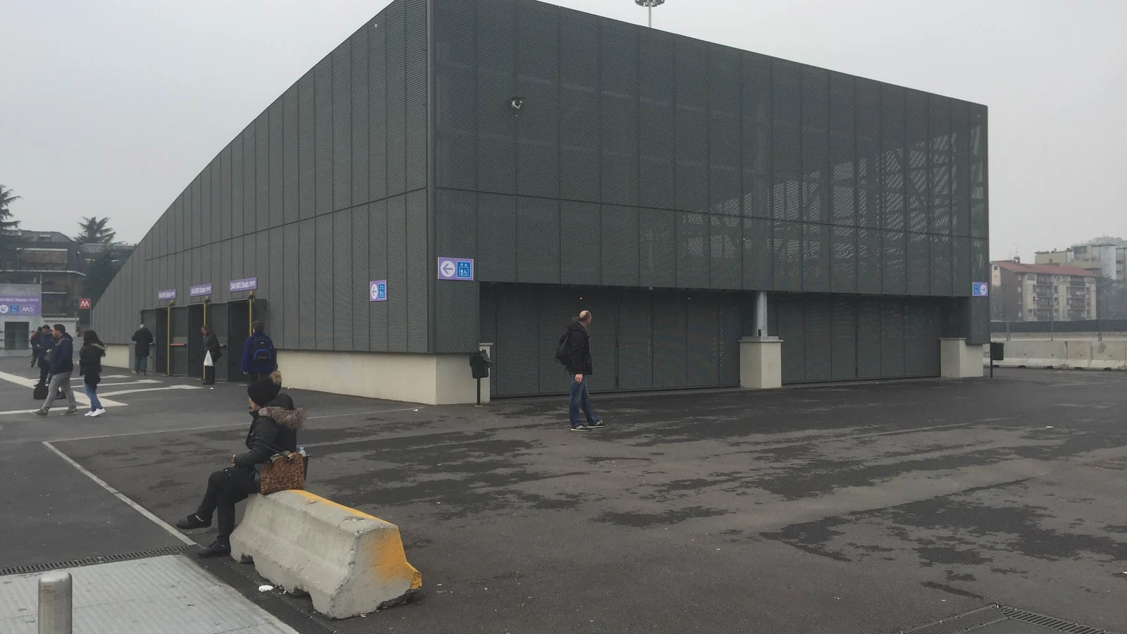 짙은 회색 외벽의 M5 San Siro Stadio역 지상 출입구와 광장