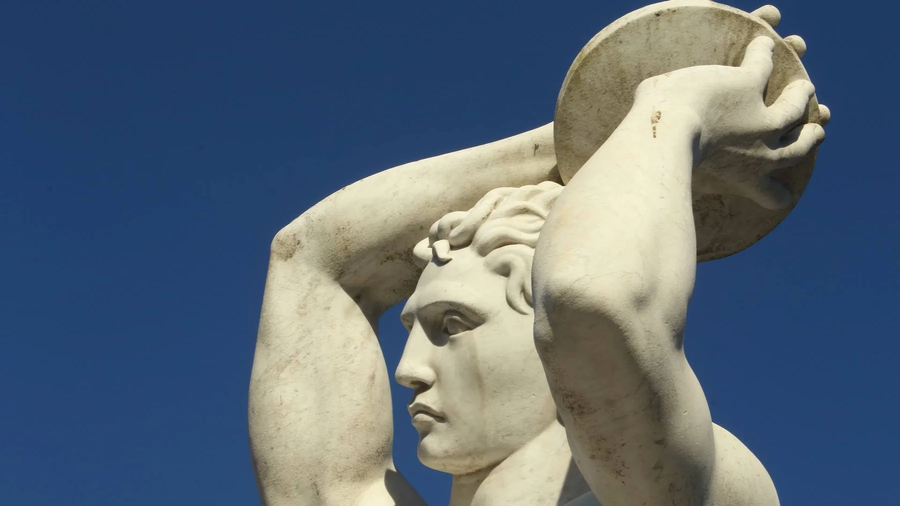 푸른 하늘을 배경으로 원반을 든 Foro Italico Stadio dei Marmi의 대리석 선수상